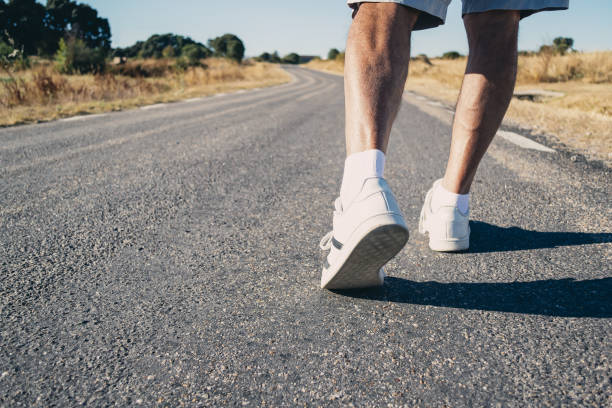 Close-up of an elderly man's legs walking down the road