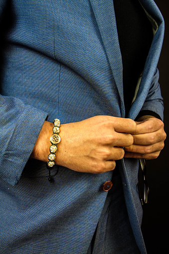 A vertical shot of a man in a suit wearing a beautiful bracelet made of stones
