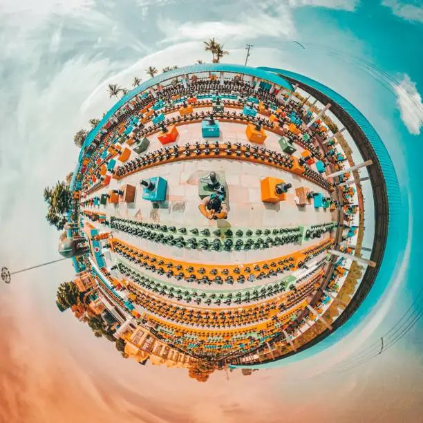 An aerial 360-degree shot of Kotilingeshwara Temple in India with palm trees and statues surrounded by a cloudy sky