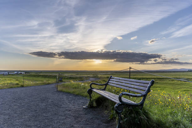 istock Wooden bench in a field covered in greenery under the sunlight in Iceland 1438084807