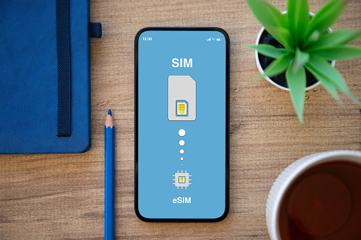 phone with Sim card replacement on eSim on screen background table in office