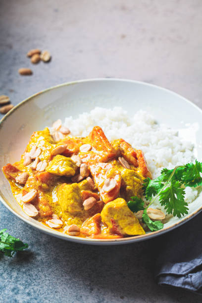 istock Thai chicken and peanut curry with rice in gray bowl, dark background. 1438085411