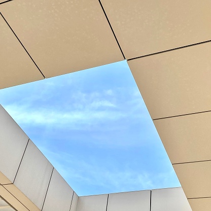 A low angle shot of a skylight window in a ceiling with a view of a blue sky