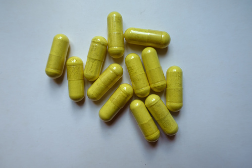 Top view of handful of greenish yellow capsules of quercetin dietary supplement