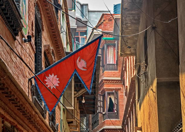 Flag of Nepal among buildings and messy cables in a narrow street of Lalitpur, Kathmandu valley, Nepal stock photo