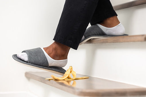 Banana peels are placed on the stairs of the house to risk accidents. The young man was about to step on a banana peel and slipped and was injured.