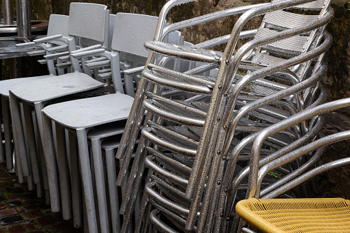 chairs folded. stainless steel polished tables in front of a cafe wet from rain and dew. the season of outdoor terraces ends.