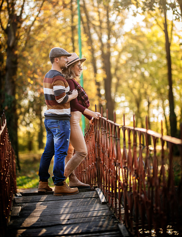 Young couple enjoying walk across the wooden bridge in the nature