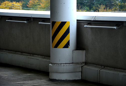 column made of reinforced concrete with stripes as protection against breaking. Obstacles such as support columns need to be protected from collisions where there is more vehicle traffic