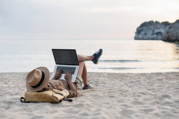 istock Young woman using laptop by the sea 1438099274