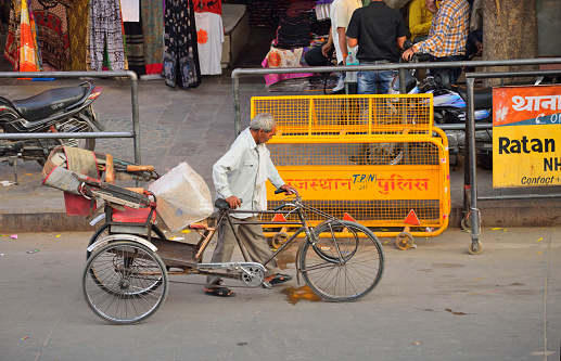 Jaipur, India - October 31, 2017: A rickshaw puller pulling his vehicle along the road carrying goods.