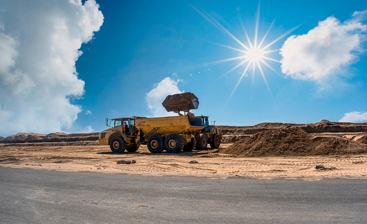 excavator loading sand in a truck, building infrastructure in the desert, Namibian roads