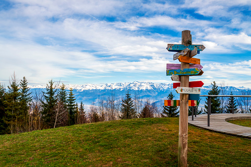Saint Nizier de Moucherotte France 11 2021 colorful signpost with major world capitals, view of the mountains from Saint Nizier du Moucherotte, row of fir trees and cloudy sky