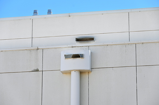 Metal box gutter and down spout on the side of a building