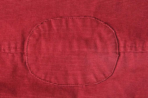 Velvet oval patch on the sleeve of the jacket close-up. Red background of soft cotton material