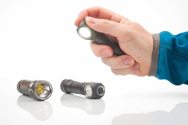 istock hand holds a flashlight against the background of other flashlights on a white background. camping and household item. 1438110699