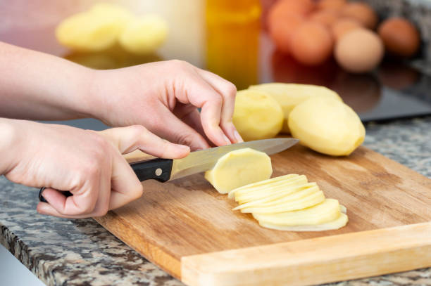 istock oman cutting up potatoes on a cutting board 1438111058