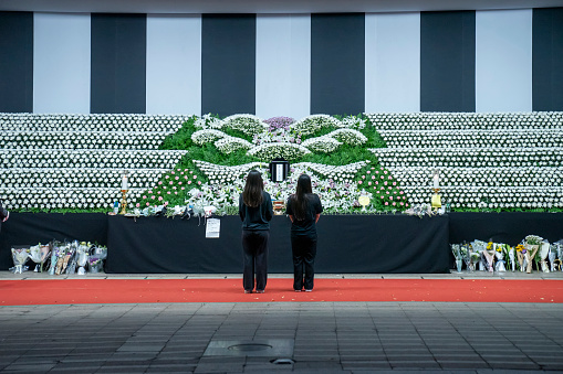 Seoul, South Korea - October 31, 2022: Mourners stand before an altar set up in front of the Seoul City Hall building at night.