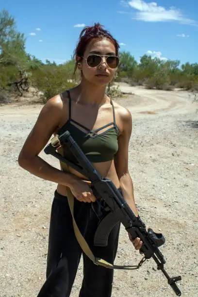 A Caucasian Latina woman with a Russian AK-47 assault rifle with American holosight in Arizona