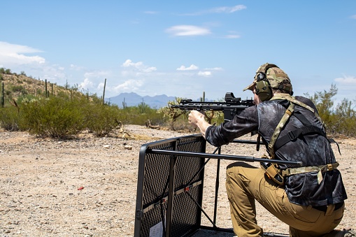 A Caucasian Man shooting with a heavily customized AR-15 Pistol SBR with a holosight weapon in Arizona Desert