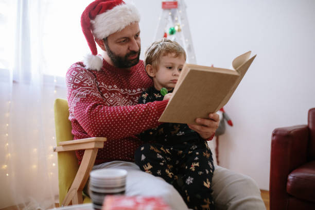 Little boy and his father are reading a book during Christmas time stock photo