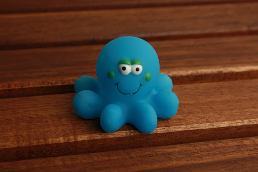 A closeup shot of a rubber blue octopus toy on a wooden surface