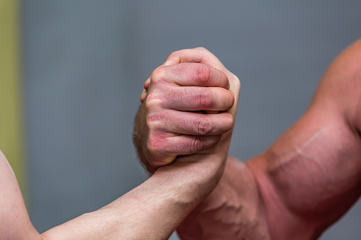 A close-up shot of strong mans' muscles during an arm-wrestling fight