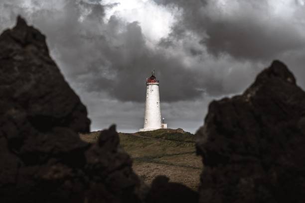 istock Dramatic view of a lighthouse standing against the dark stack of clouds 1438114160