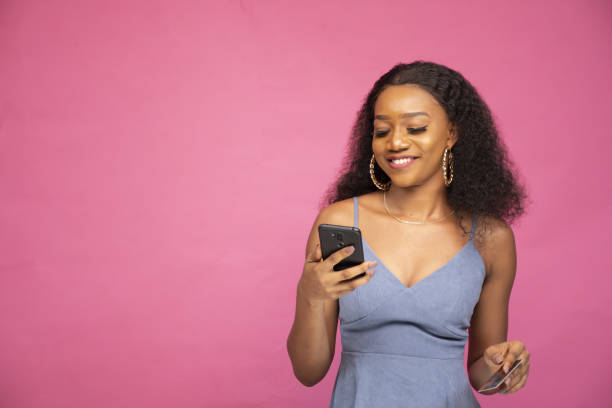 istock Young African female shopping online using her smartphone 1438114401