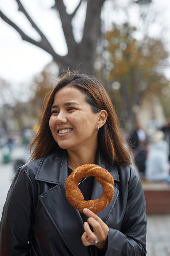 beautiful girl in dark casual clothes smiling with simit and looking side