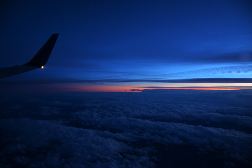 A beautiful shot of an airplane flying above white clouds at sunset