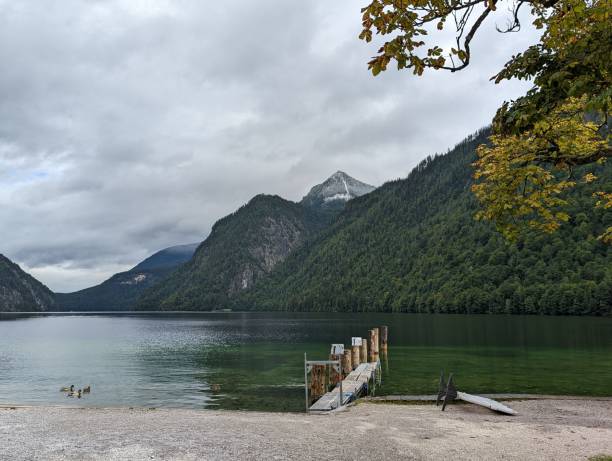 istock Jetty lake shore with Alps mountains under cloudy sky during fall season 1438117267