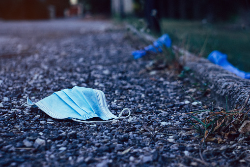 A used protective face mask haphazardly strewn on the ground