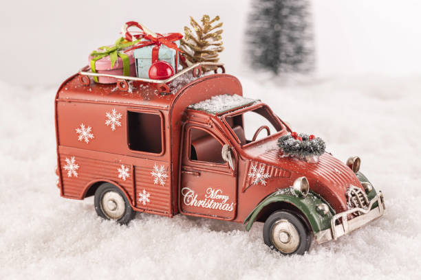 istock Small car toy decorated with ornaments on artificial snow with a Christmas tree in the background 1438118873