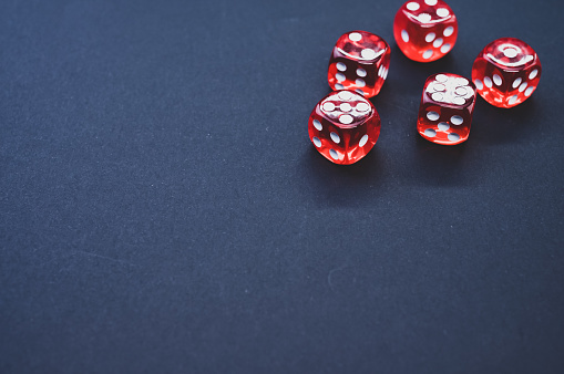 A closeup of  red rolling dice on a dark  background