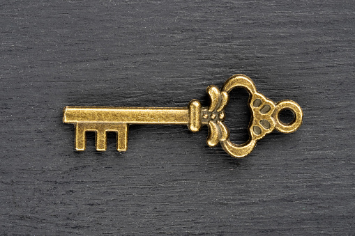 Bronze vintage antique key on black wooden background. Old keys concept