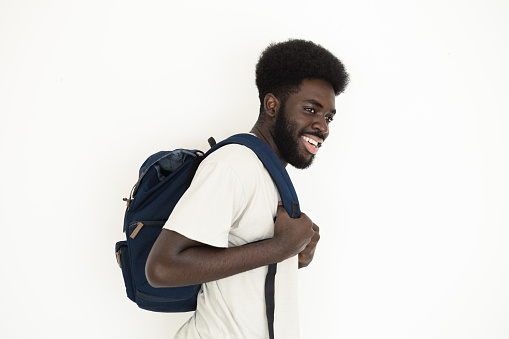 Studio portrait of a young, smiling African-American man with a backpack