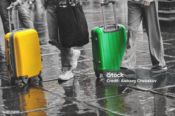 Tourists Travel Around The City With A Green And Yellow Suitcase In The Rain Stock Photo - Download Image Now