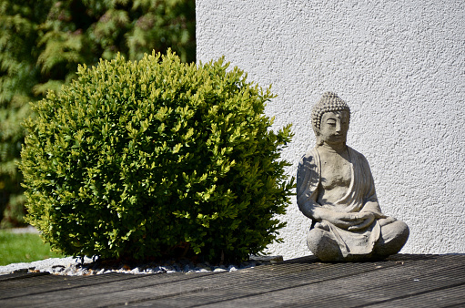 A little statue of Buddha outside the house on a sunny day