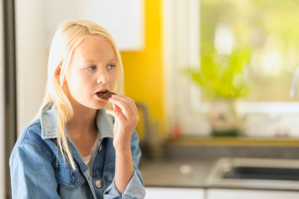 istock Fair haired young girl sitting in her kitchen 1438129190