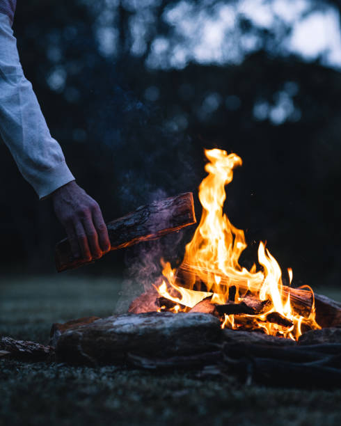 istock Man putting a log in a bonfire in the evening 1438131623