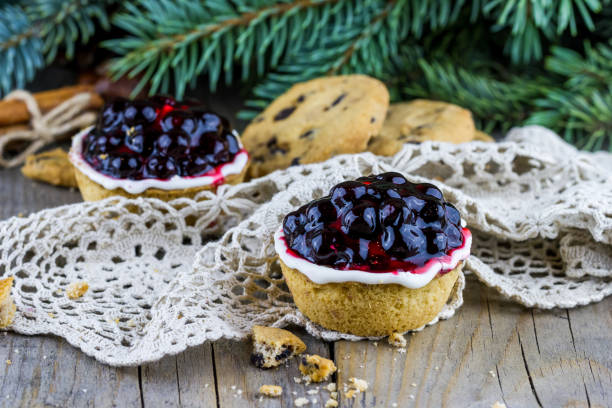 Christmas (New Year) composition. Top view chocolate chip cookies with currant cakes, cinnamon sticks and fur-tree branches on wooden background