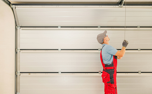 Automatic Residential Garage Doors Installation Performed by Professional Caucasian Technician in His 40s.