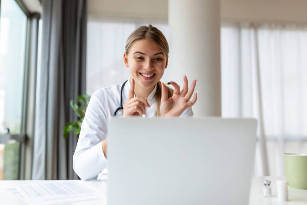 istock Attractive female doctor talking while explaining medical treatment to patient through a video call with laptop in the consultation. 1438139326