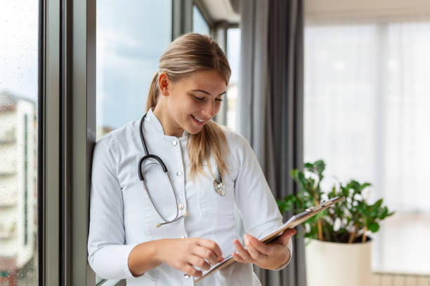 istock Confident smiling doctor posing and looking at camera with stethoscope in her hands. Friendly female doctor smiling. Doctor with stethoscope around her neck 1438139363
