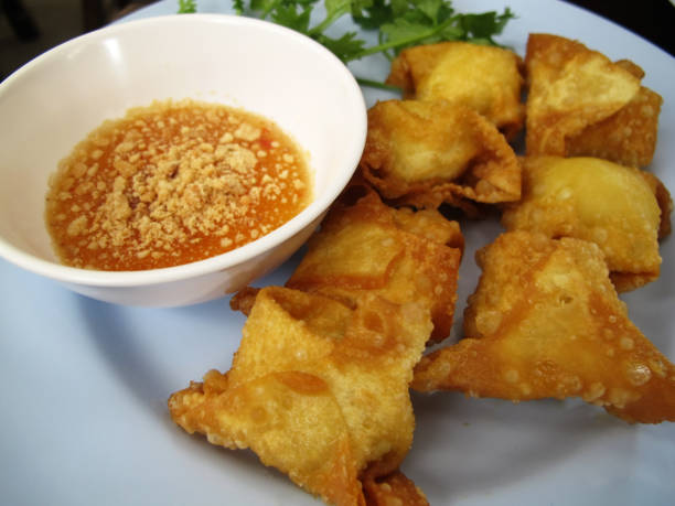 istock Deep fried pork wonton dumplings with dip spicy sweet sauce serve with side dish vegetables for customer thai people eat and drinks at cafe restaurant shop in Bangkok, Thailand 1438140045