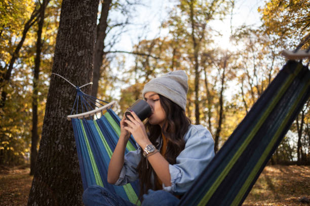istock Woman sitting on a hammock and drinking coffee 1438142448