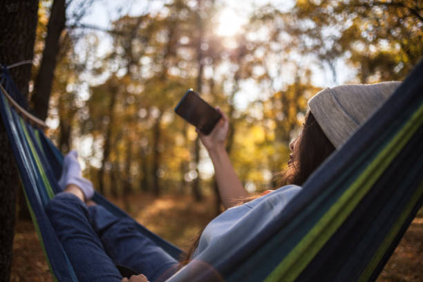 istock Woman sitting on a hammock and taking a selfie 1438142535