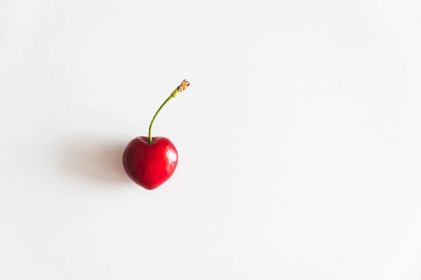 istock Close-up fresh red cherry of heart shape on white table. Top view 1438143302