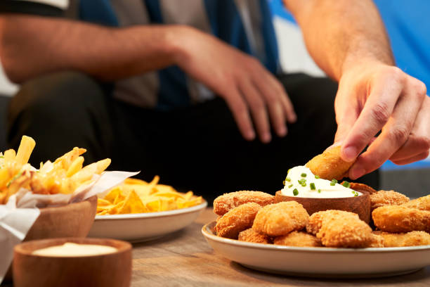 un fan de football mange des collations servies sur une table en bois - orange sauce photos et images de collection